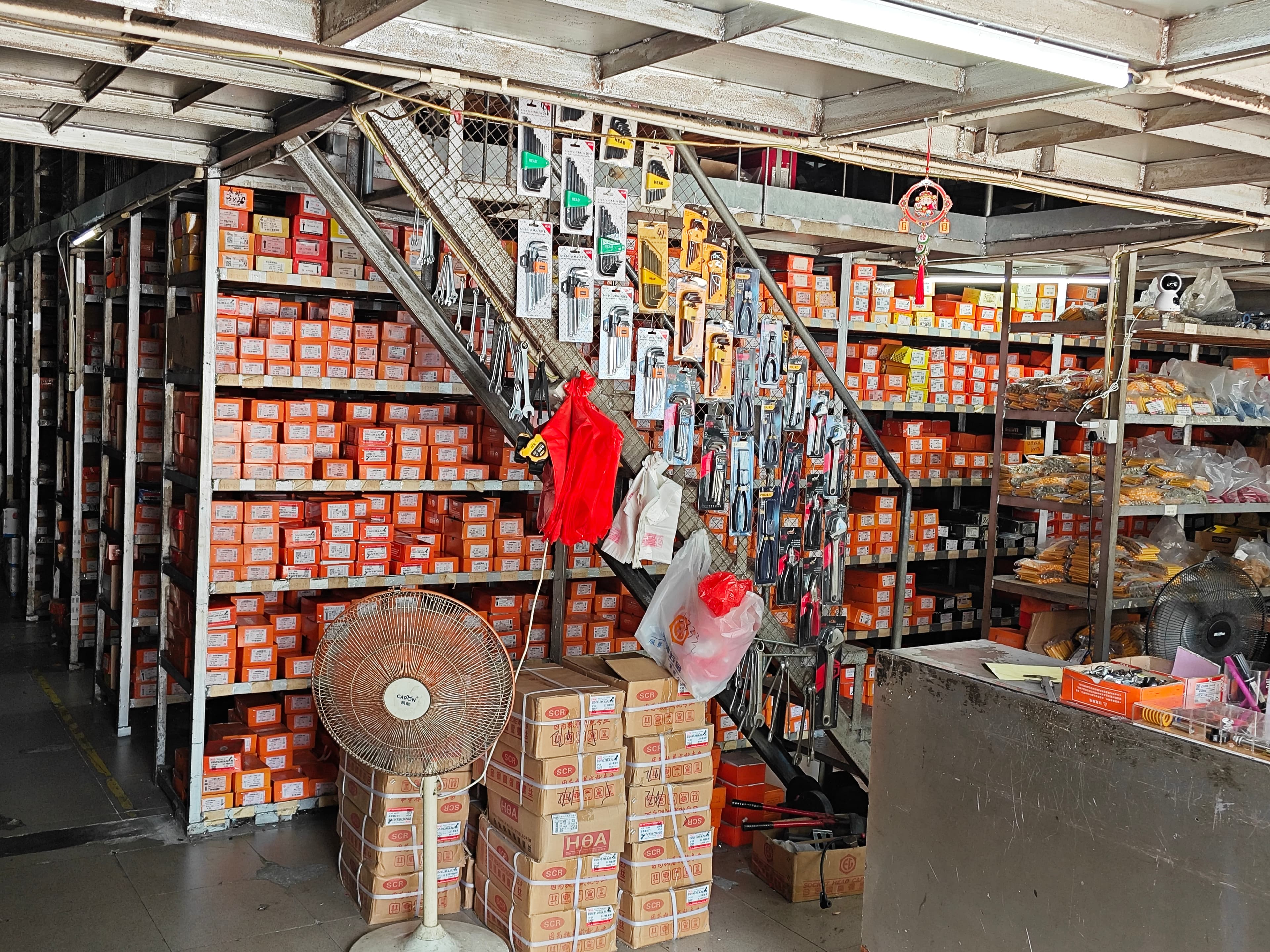 Packaged hex keys and hand tools hanging beside shelves of boxed fasteners.