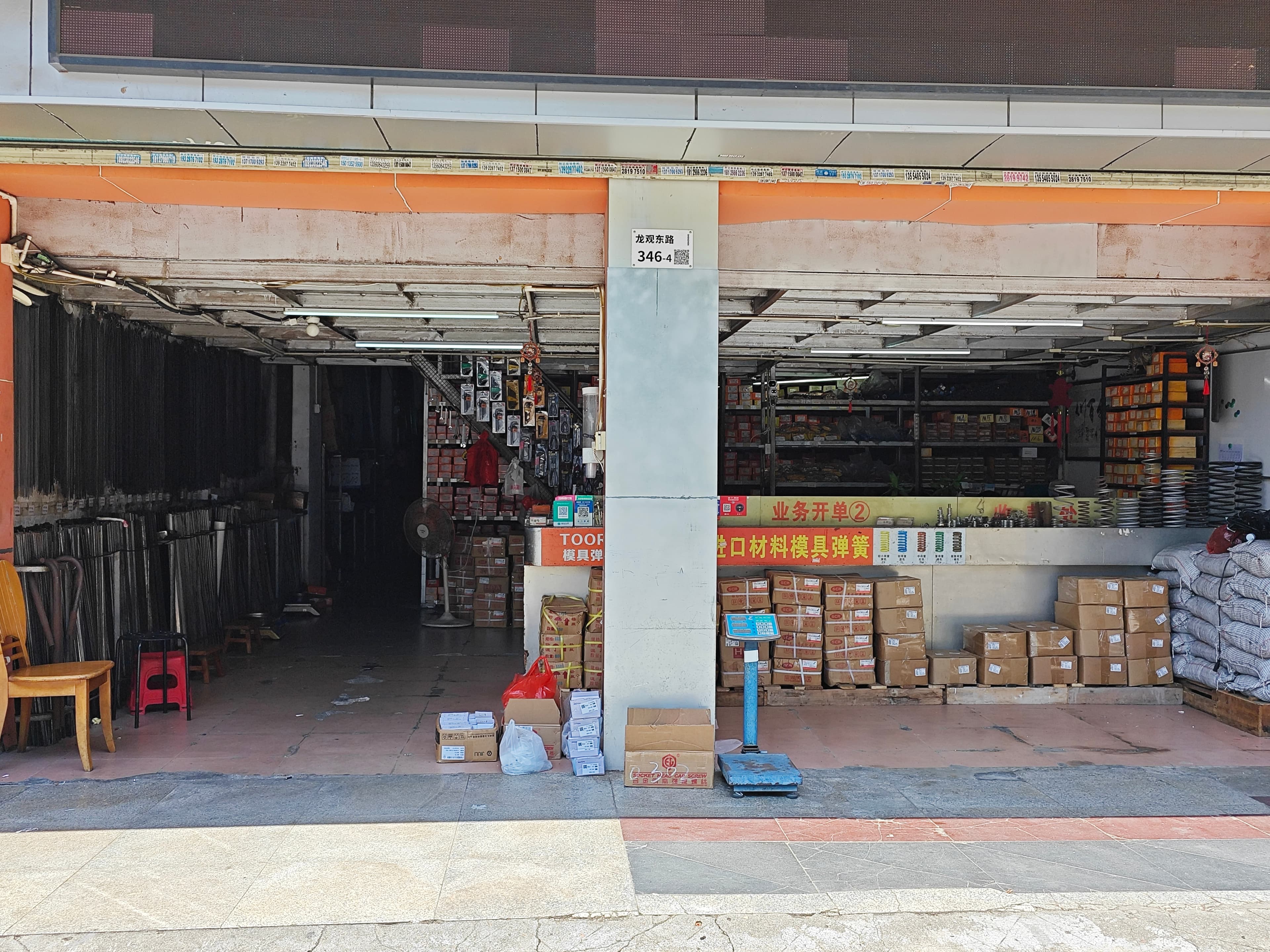 Front view of the open shop entrance, counter, packed cartons and floor scale.