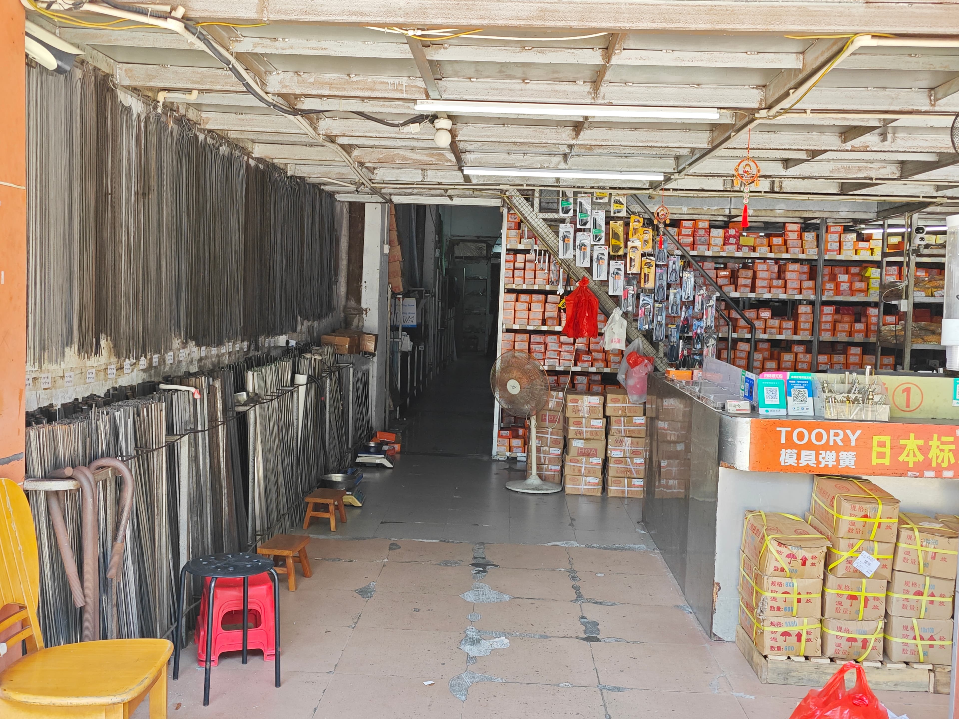 Long metal rods displayed vertically along the shop wall beside the entrance aisle.